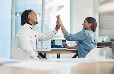 Buy stock photo Shot of two businesspeople giving each other a high five in an office
