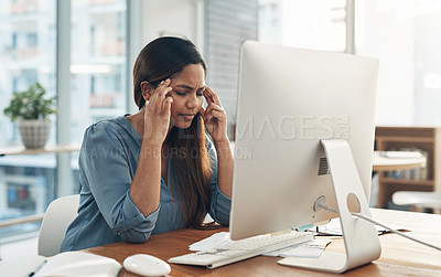 Buy stock photo Shot of a young businesswoman experiencing a headache while working on a computer in an office