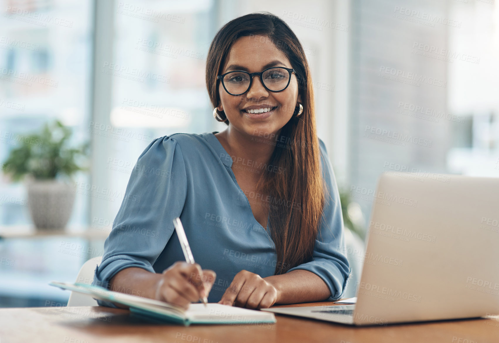 Buy stock photo Portrait of a young businesswoman writing notes while working in an office