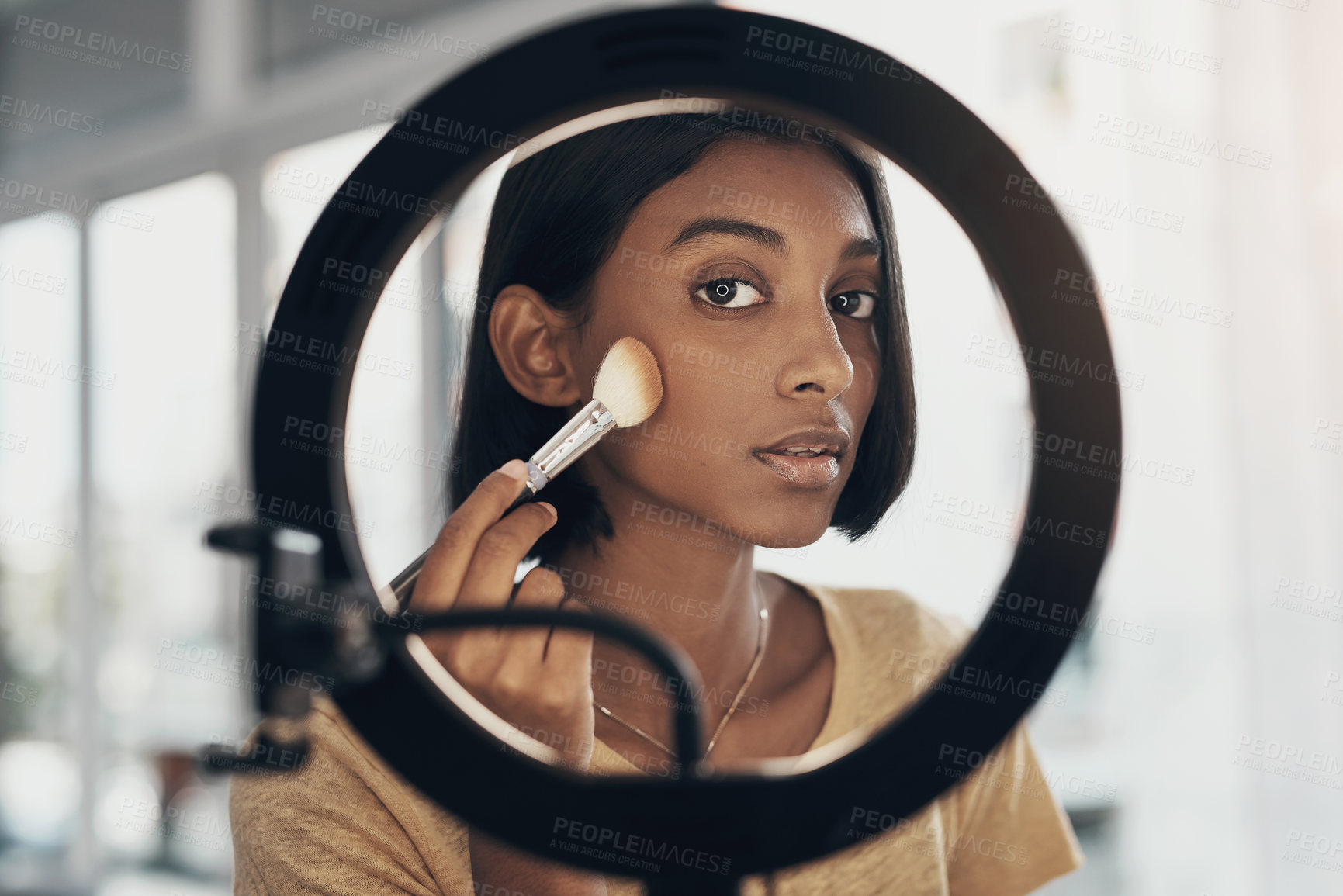 Buy stock photo Shot of a young woman applying makeup while filming a beauty tutorial at home