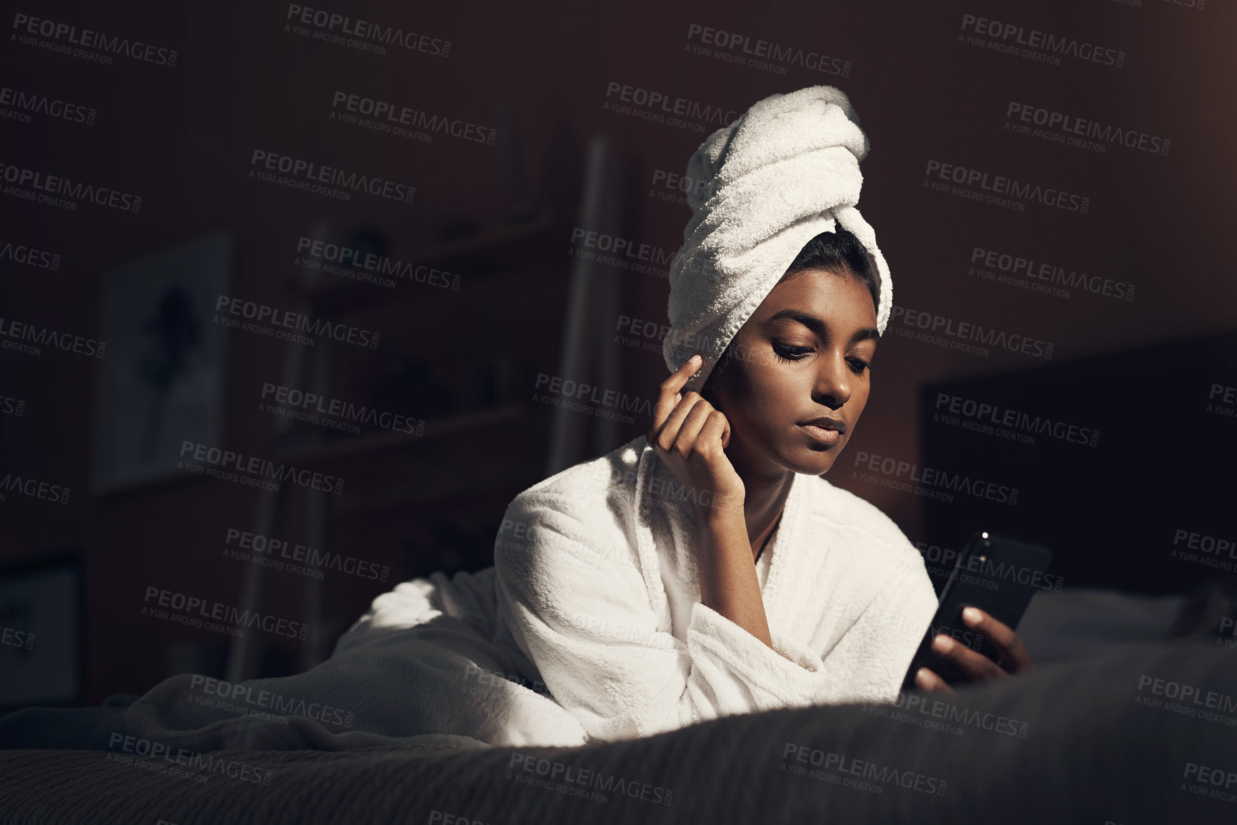 Buy stock photo Shot of a young woman using a smartphone while going through her beauty routine at home