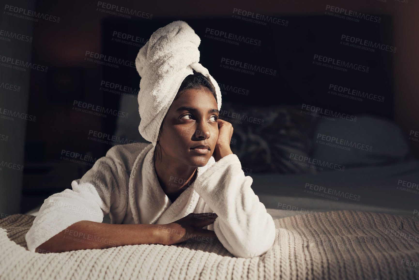 Buy stock photo Shot of a young woman relaxing on her bed while going through her beauty routine at home