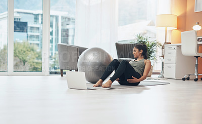 Buy stock photo Shot of a woman working out in her living room with her laptop in front of her