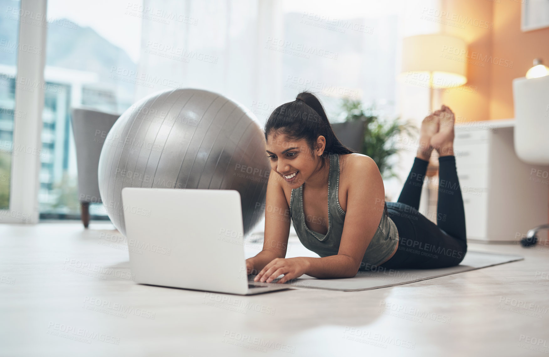 Buy stock photo Shot of a woman using her laptop while exercising at home