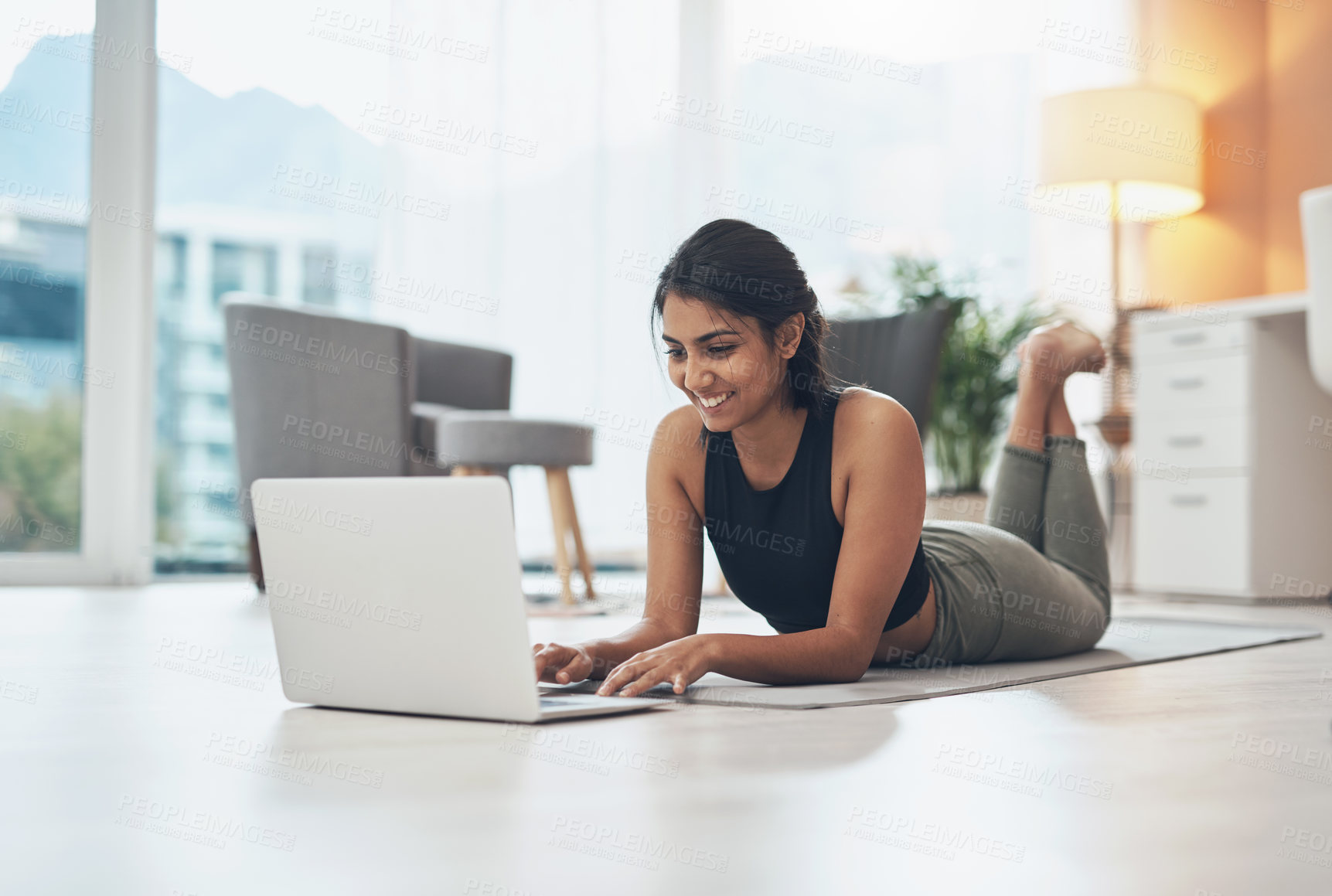 Buy stock photo Shot of a woman using her laptop while exercising at home