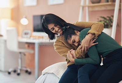 Buy stock photo Shot of two happy young women sitting together at home