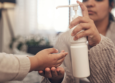 Buy stock photo Shot of a woman disinfecting her son’s hands at home