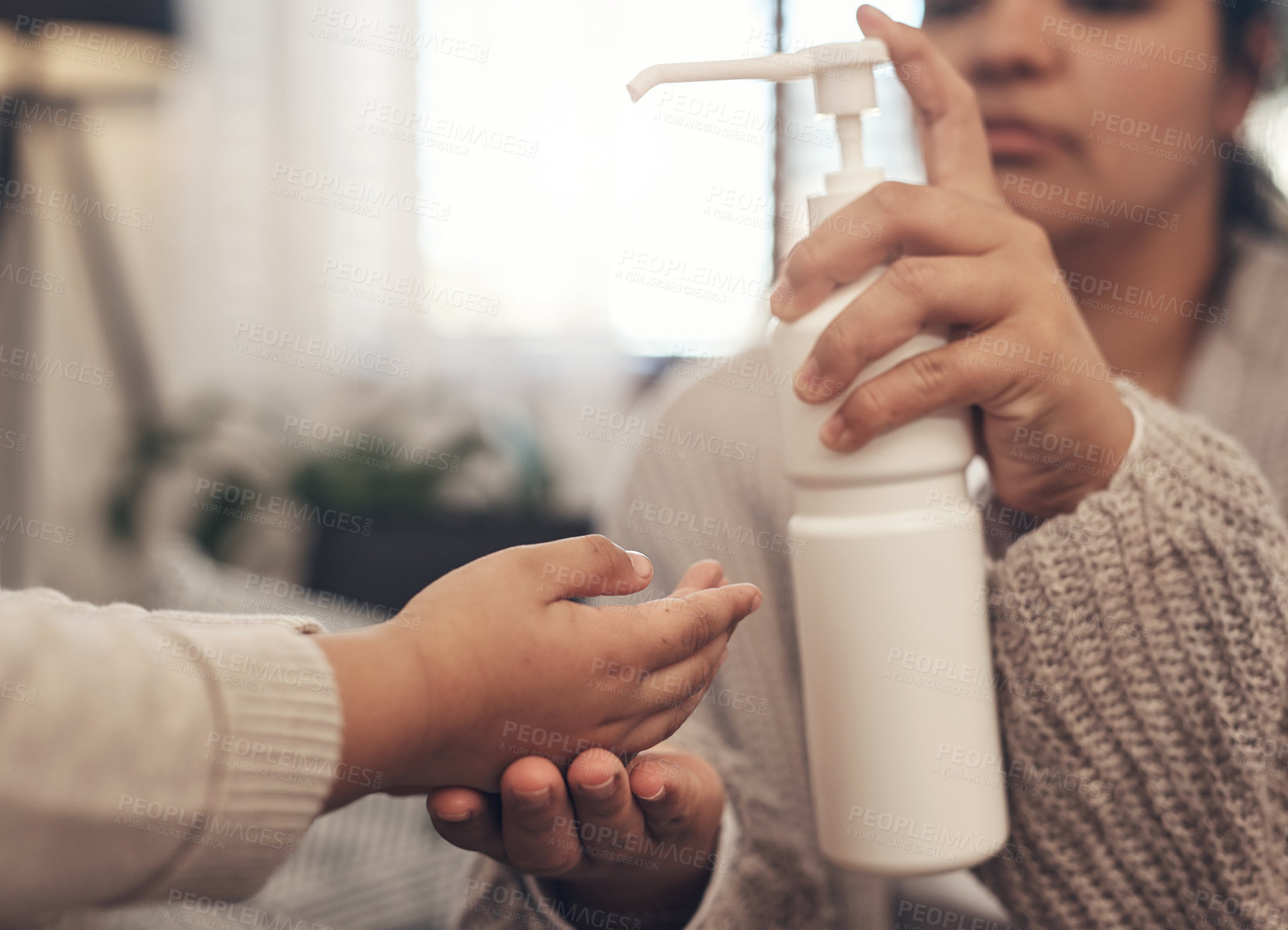 Buy stock photo Shot of a woman disinfecting her son’s hands at home