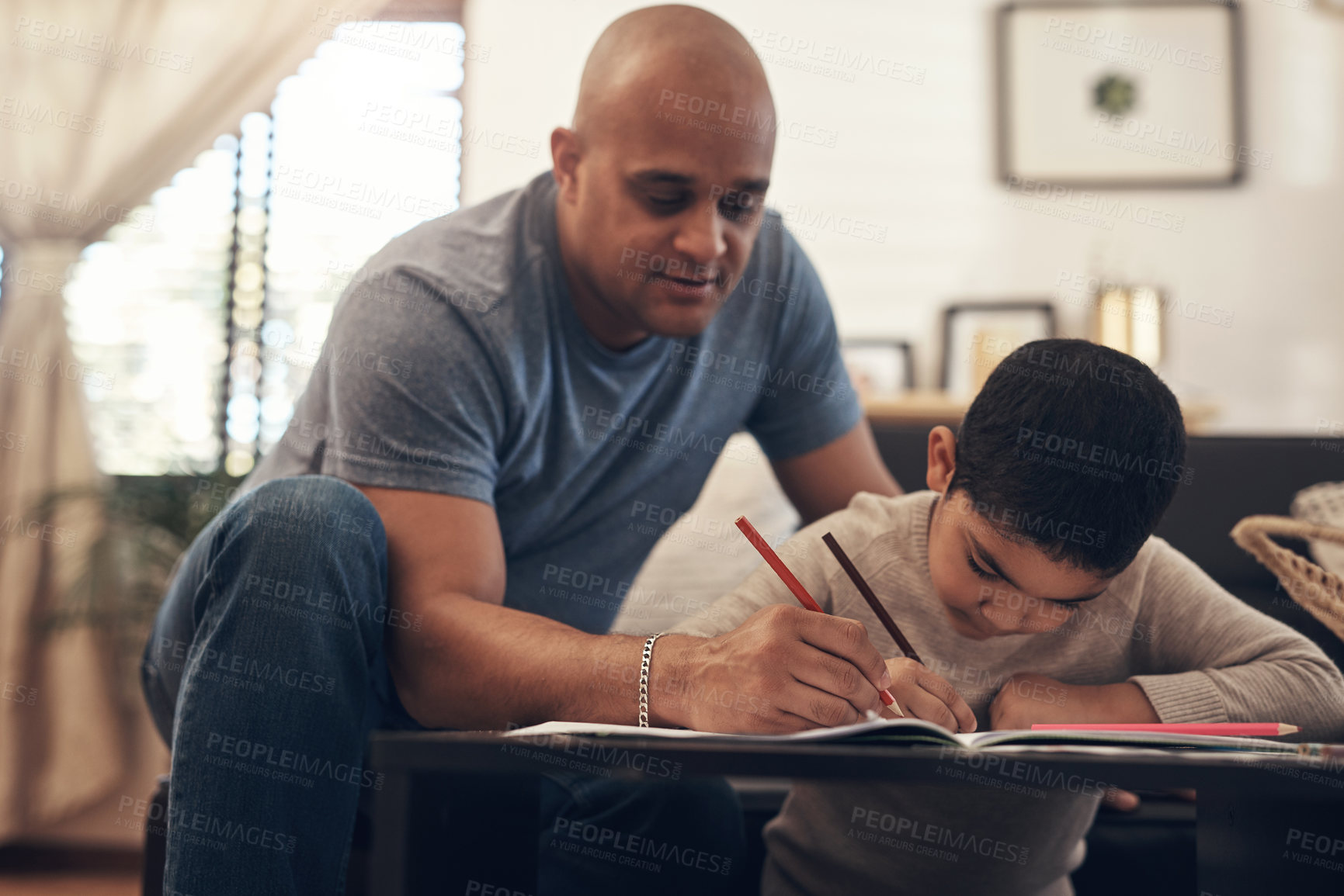 Buy stock photo Shot of an adorable little boy completing a school assignment with his father at home