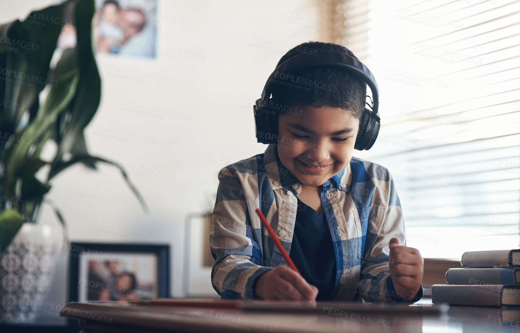 Buy stock photo Shot of an adorable little boy using a digital tablet and headphones while completing a school assignment at home