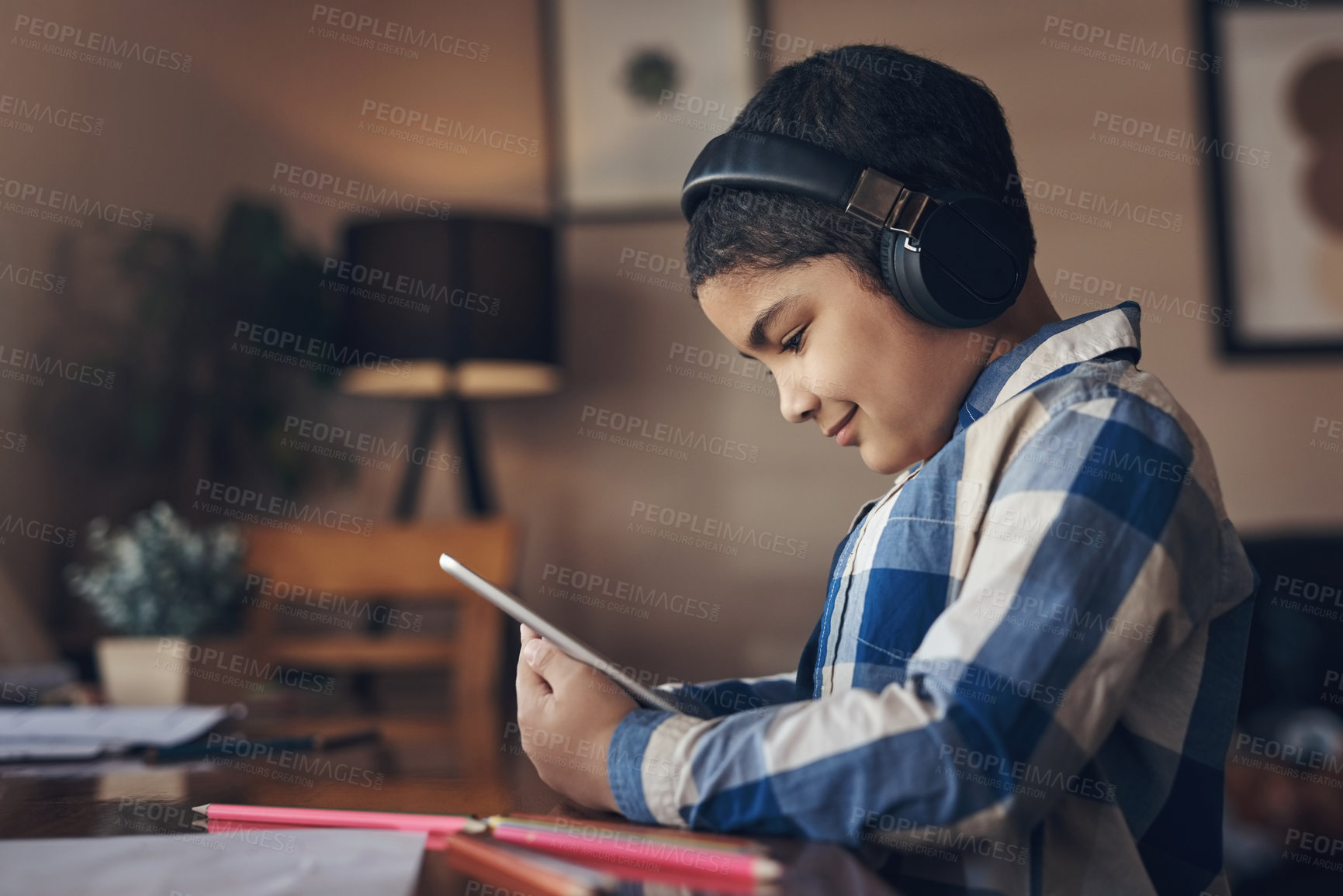 Buy stock photo Shot of an adorable little boy using a digital tablet and headphones while completing a school assignment at home