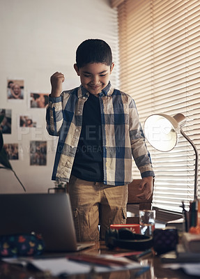 Buy stock photo Shot of an adorable little boy using a laptop and cheering while completing a school assignment at home
