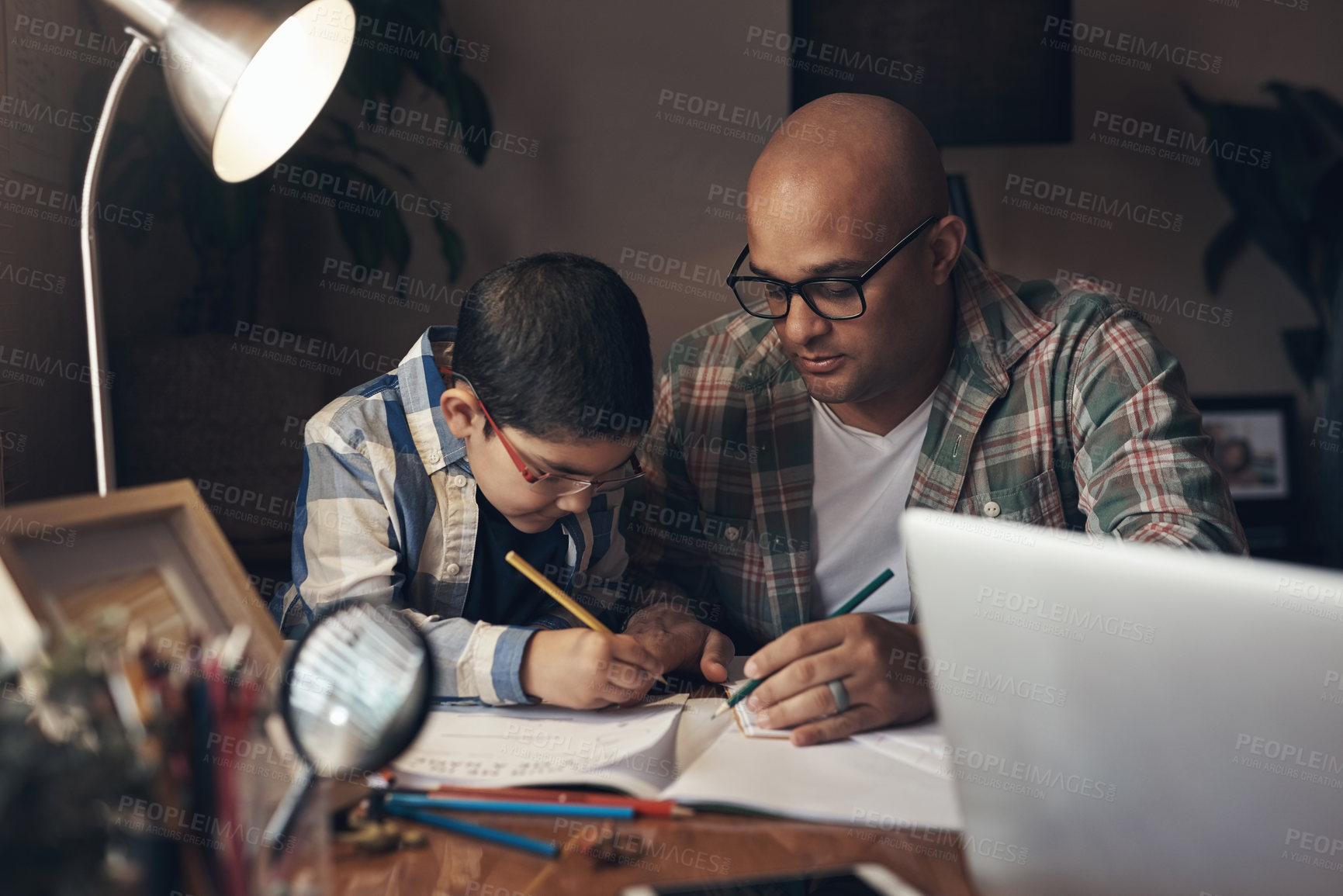 Buy stock photo Shot of an adorable little boy completing a school assignment with his father at home