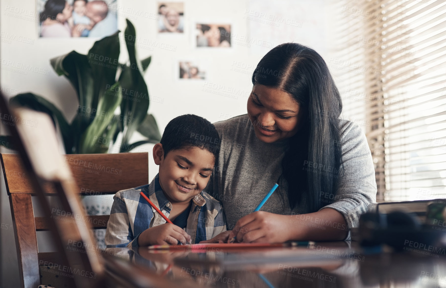 Buy stock photo Shot of an adorable little boy completing a school assignment with his mother at home