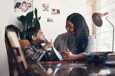 Buy stock photo Shot of an adorable little boy completing a school assignment with his mother at home