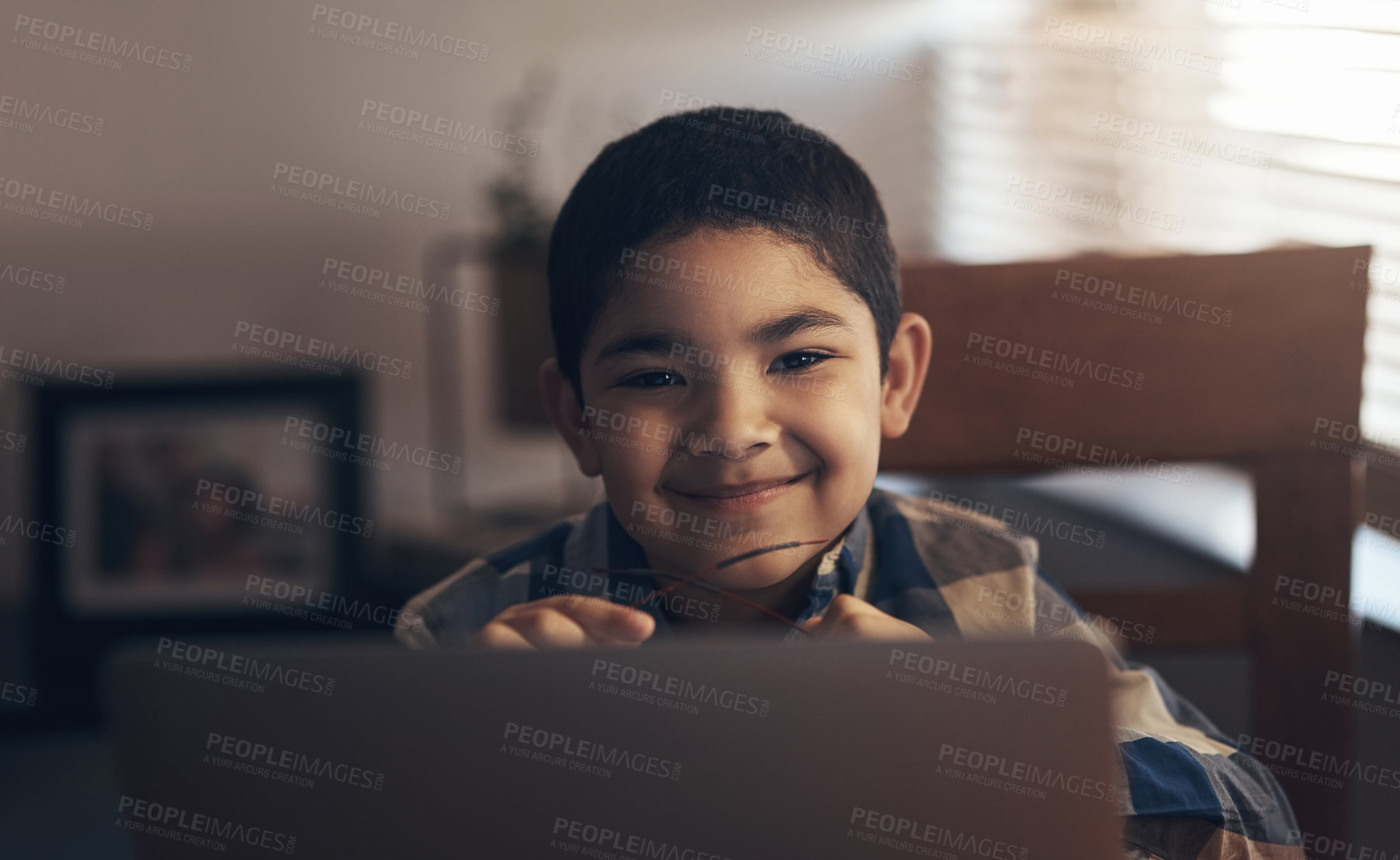 Buy stock photo Shot of an adorable little boy using a laptop while completing a school assignment at home