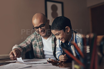 Buy stock photo Shot of an adorable little boy completing a school assignment with his father at home