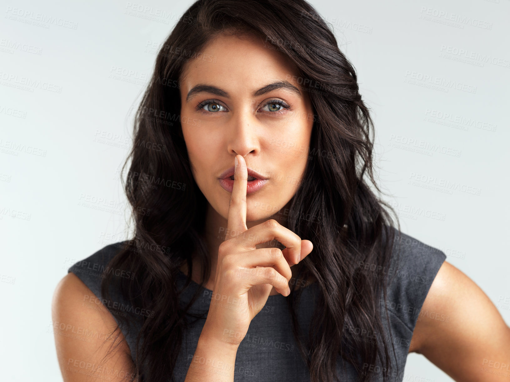 Buy stock photo Shot of a beautiful young woman posing with her finger on her lips