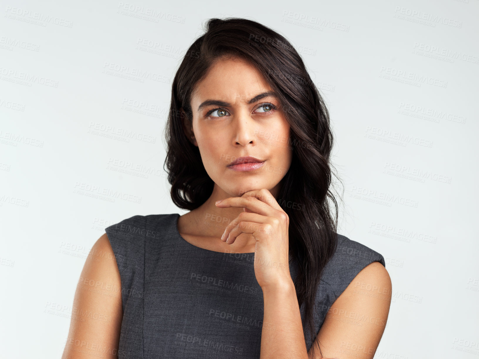 Buy stock photo Shot of a beautiful young woman looking thoughtful while standing against a white background