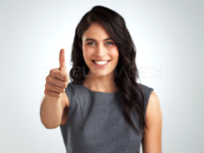 Buy stock photo Shot of a young woman showing thumbs up while standing against a grey background