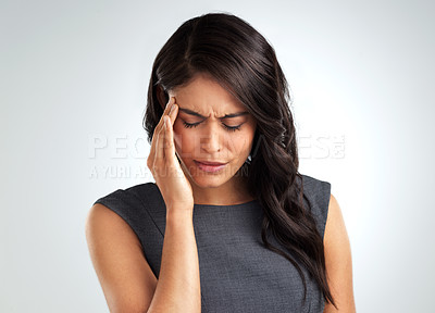 Buy stock photo Shot of a young woman suffering from a headache while standing against a white background