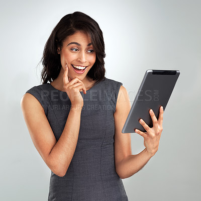 Buy stock photo Shot of a beautiful young woman using a digital tablet while standing against a grey background