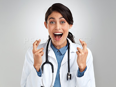 Buy stock photo Studio portrait of a young doctor crossing her fingers against a grey background