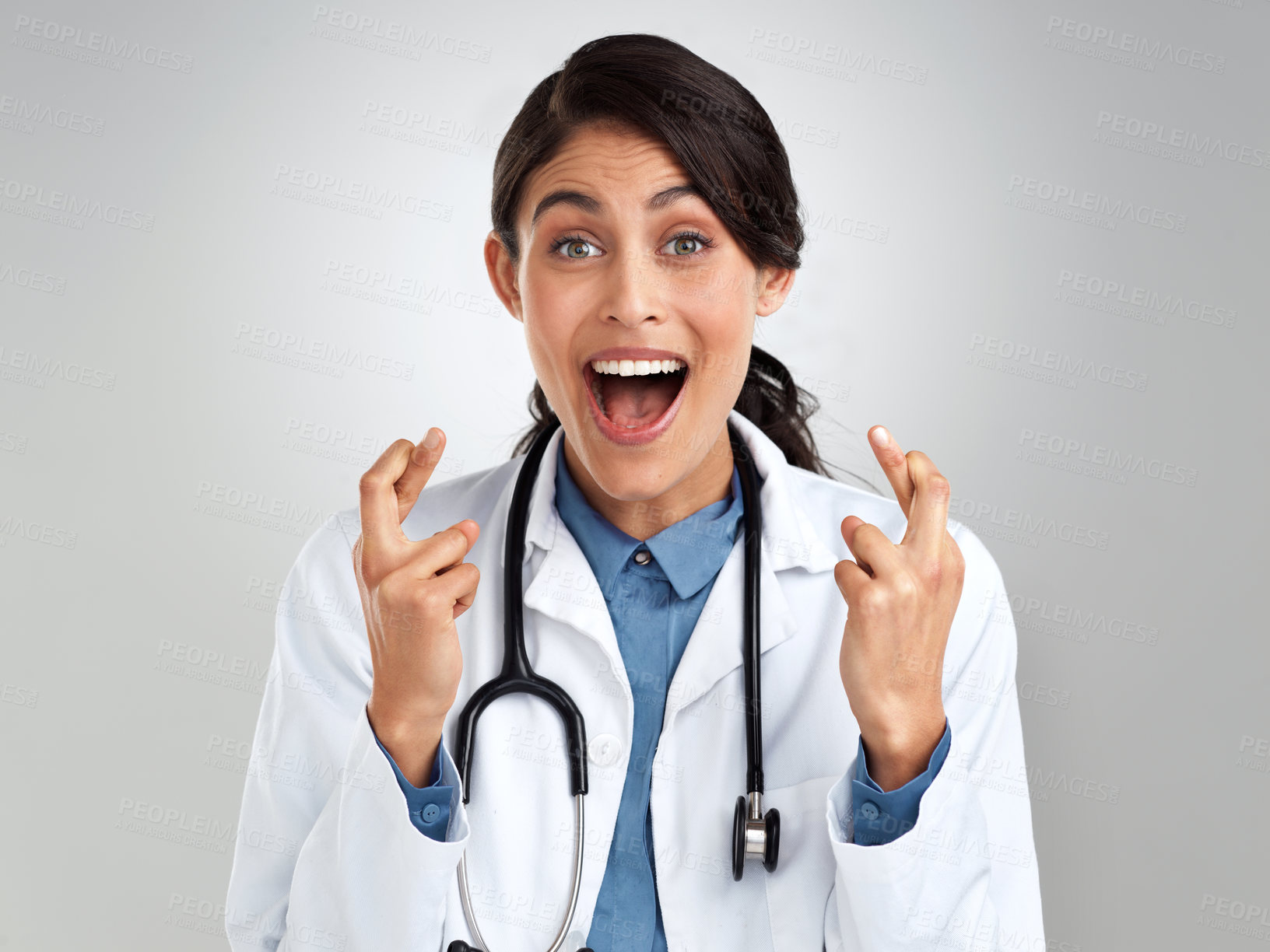 Buy stock photo Studio portrait of a young doctor crossing her fingers against a grey background