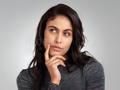 Buy stock photo Shot of a beautiful young woman looking thoughtful while standing against a white background