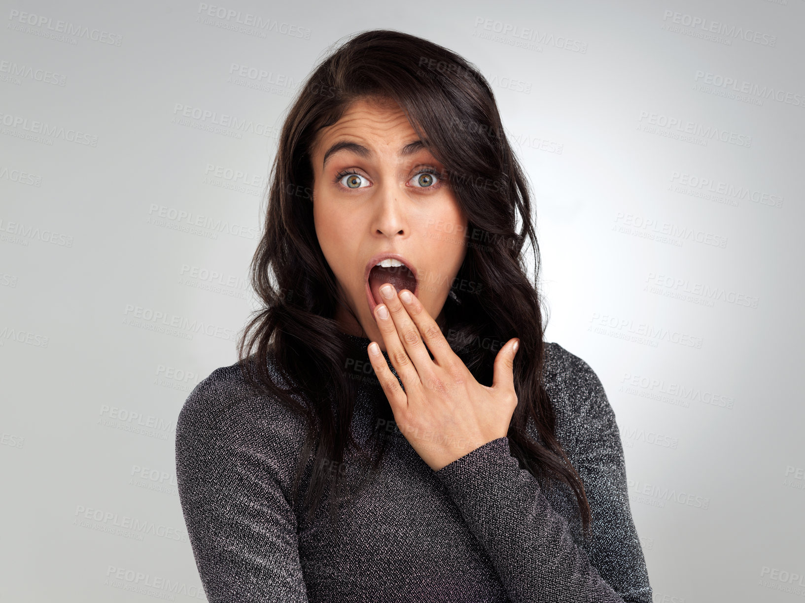 Buy stock photo Shot of a young woman looking surprised while posing against a white background