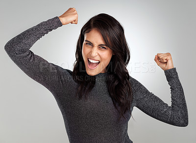 Buy stock photo Shot of a beautiful young woman looking cheerful while standing against a grey background