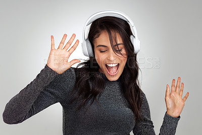 Buy stock photo Shot of a beautiful young woman wearing headphones while standing against a grey background
