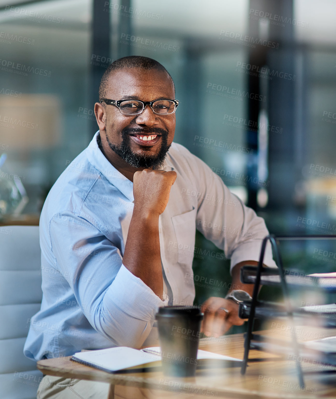 Buy stock photo Cropped portrait of a handsome mature businessman sitting alone in his office at night with his hand on his chin