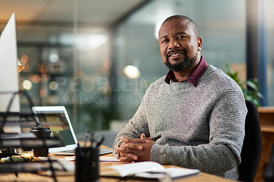 Buy stock photo Cropped portrait of a handsome mature businessman sitting alone at his desk during a late shift in the office