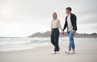 Buy stock photo Shot of a couple holding hands while strolling on the beach