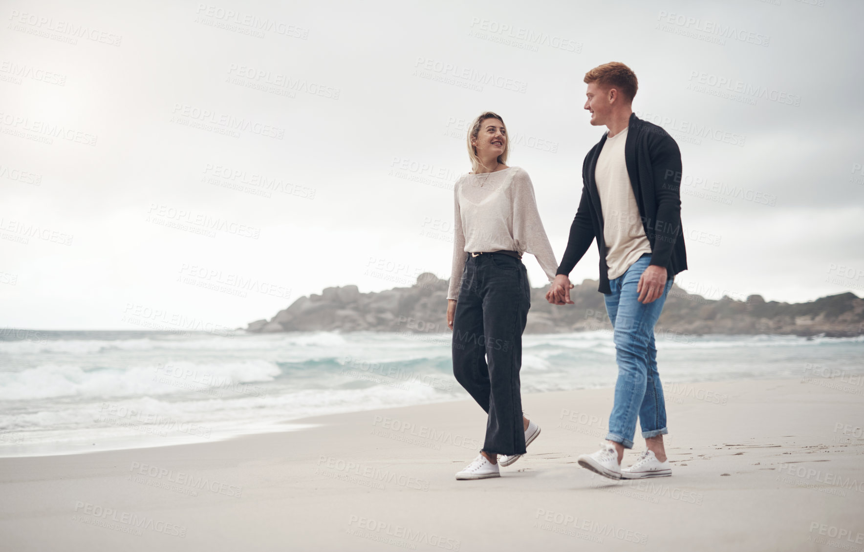 Buy stock photo Shot of a couple holding hands while strolling on the beach