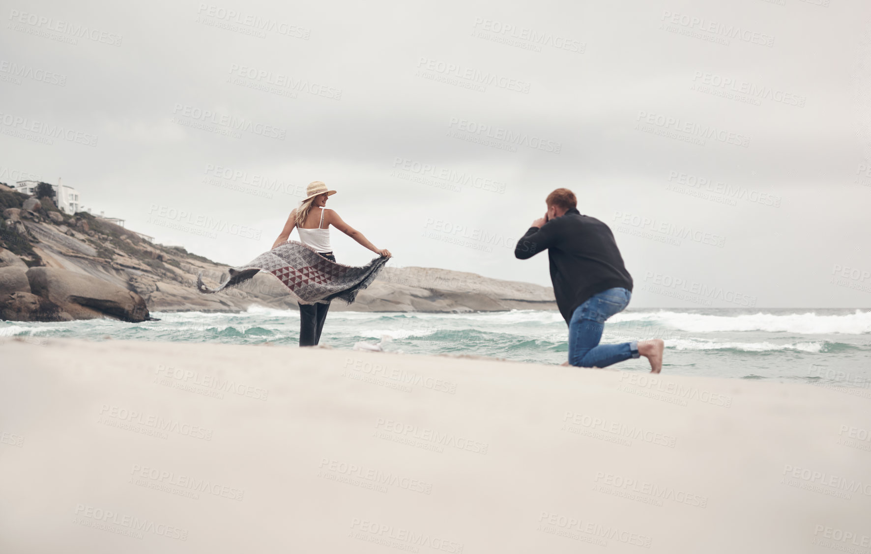 Buy stock photo Shot of a man taking pictures of his girlfriend while spending time at the beach