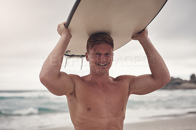 Buy stock photo Shot of a young man carrying his surfboard on his head while at the beach