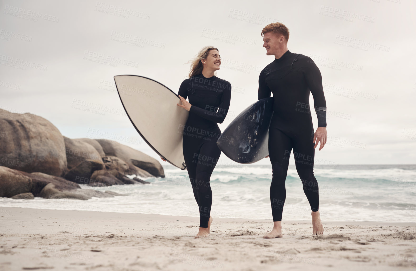 Buy stock photo Shot of a young couple out at the beach with their surfboards