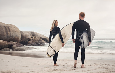 Buy stock photo Shot of a young couple out at the beach with their surfboards