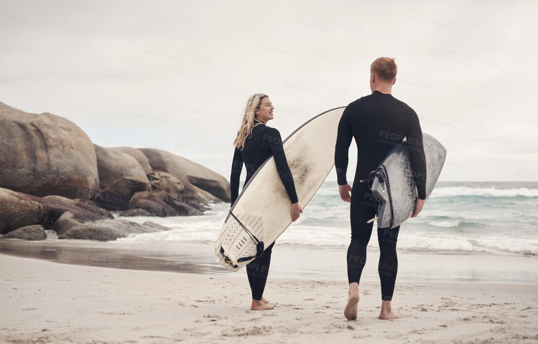 Buy stock photo Shot of a young couple out at the beach with their surfboards