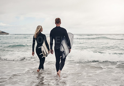 Buy stock photo Shot of a young couple out at the beach with their surfboards