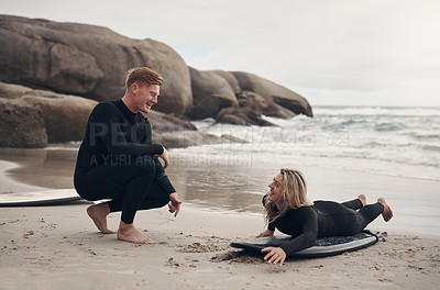 Buy stock photo Shot of a man giving a woman surfing lessons on the beach