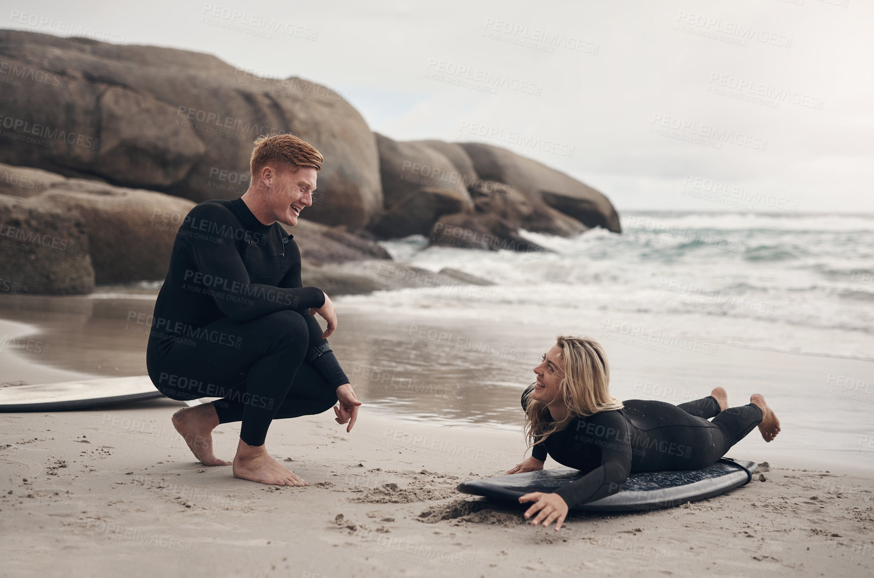 Buy stock photo Shot of a man giving a woman surfing lessons on the beach