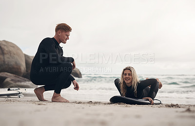 Buy stock photo Shot of a man giving a woman surfing lessons on the beach