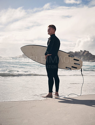 Buy stock photo Shot of a young man holding his surfboard while at the beach