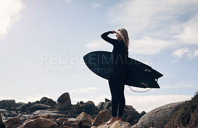 Buy stock photo Cropped shot of a young woman standing on the beach with her surfboard