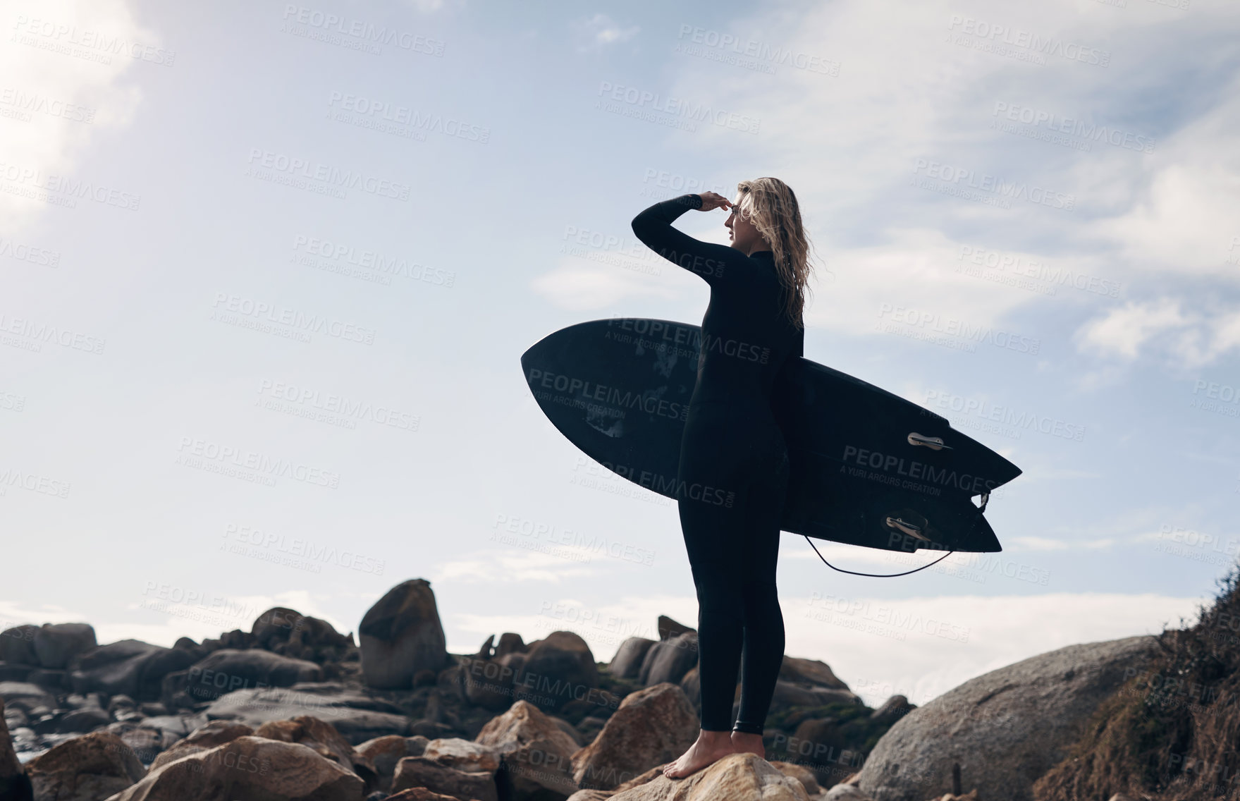 Buy stock photo Cropped shot of a young woman standing on the beach with her surfboard