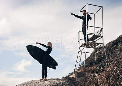 Buy stock photo Shot of two people pointing at something while standing by a lifeguard tower