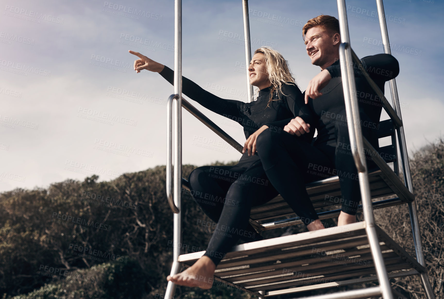 Buy stock photo Shot of two people wearing wetsuits while sitting on a lifeguard tower